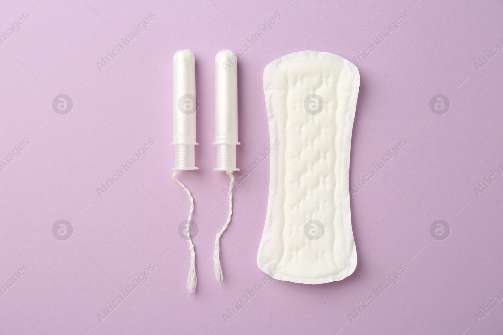 Photo of Menstrual pad and tampons on lilac background, top view