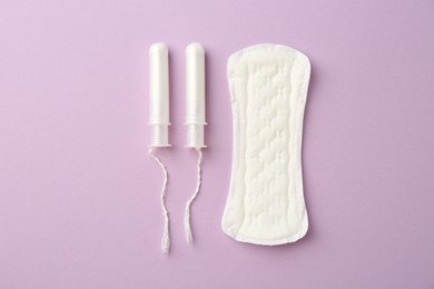 Menstrual pad and tampons on lilac background, top view