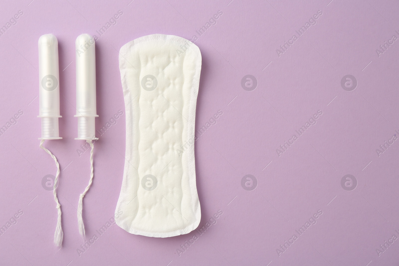 Photo of Menstrual pad and tampons on lilac background, top view. Space for text