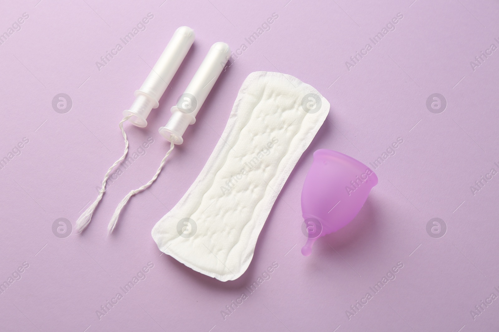 Photo of Menstrual pad, cup and tampons on lilac background