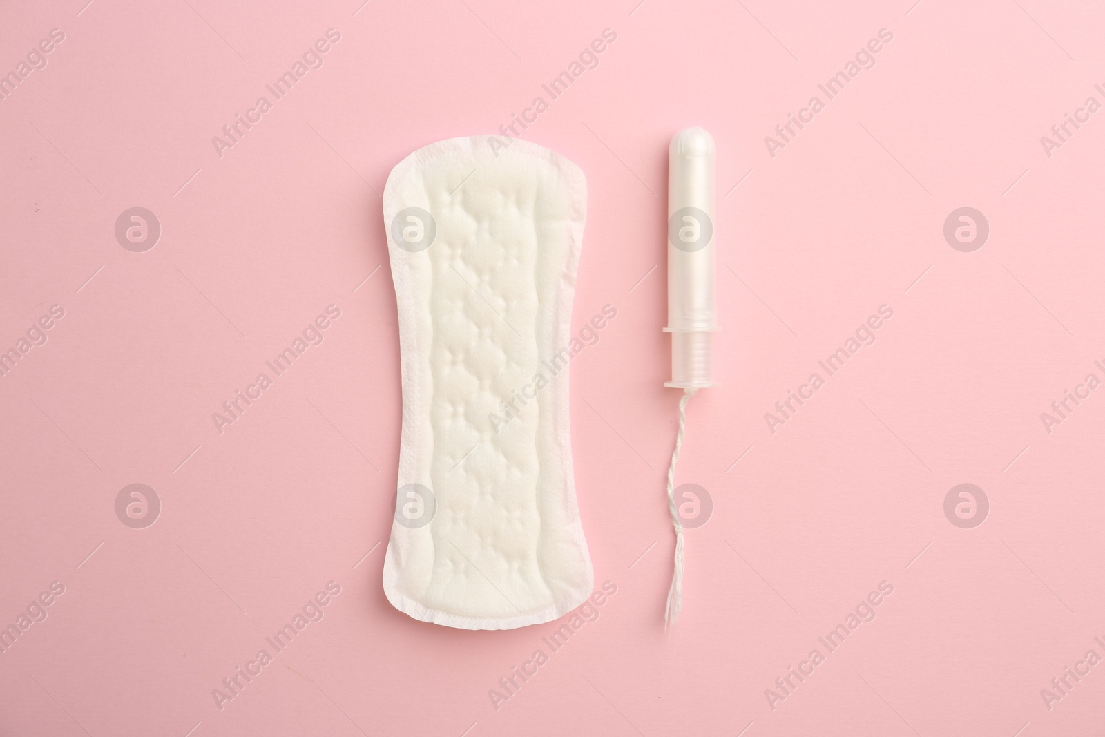 Photo of Menstrual pad and tampon on light pink background, top view