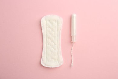 Photo of Menstrual pad and tampon on light pink background, top view