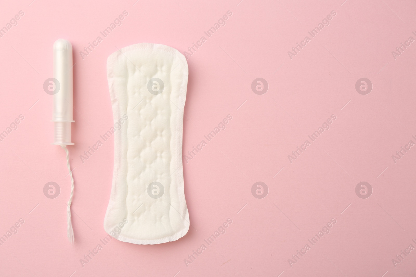 Photo of Menstrual pad and tampon on light pink background, top view. Space for text