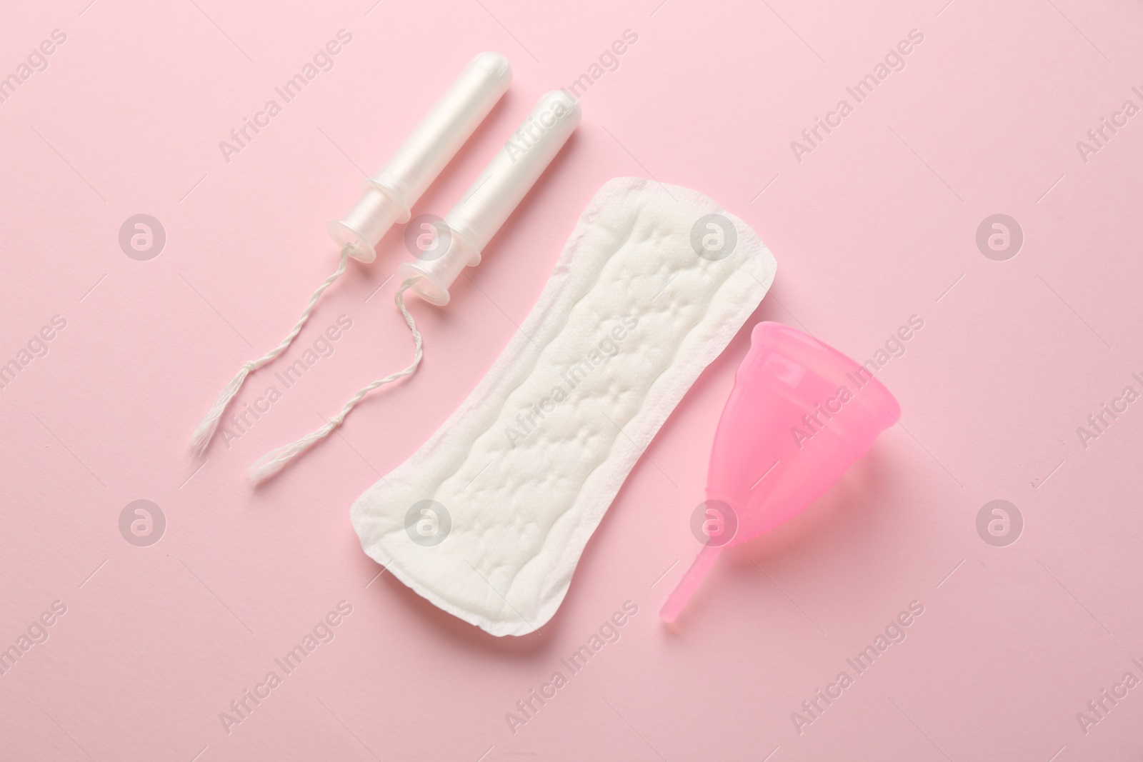 Photo of Menstrual pad, cup and tampons on light pink background