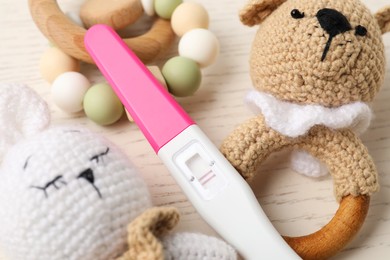 Photo of Pregnancy test and baby toys on white wooden table, closeup