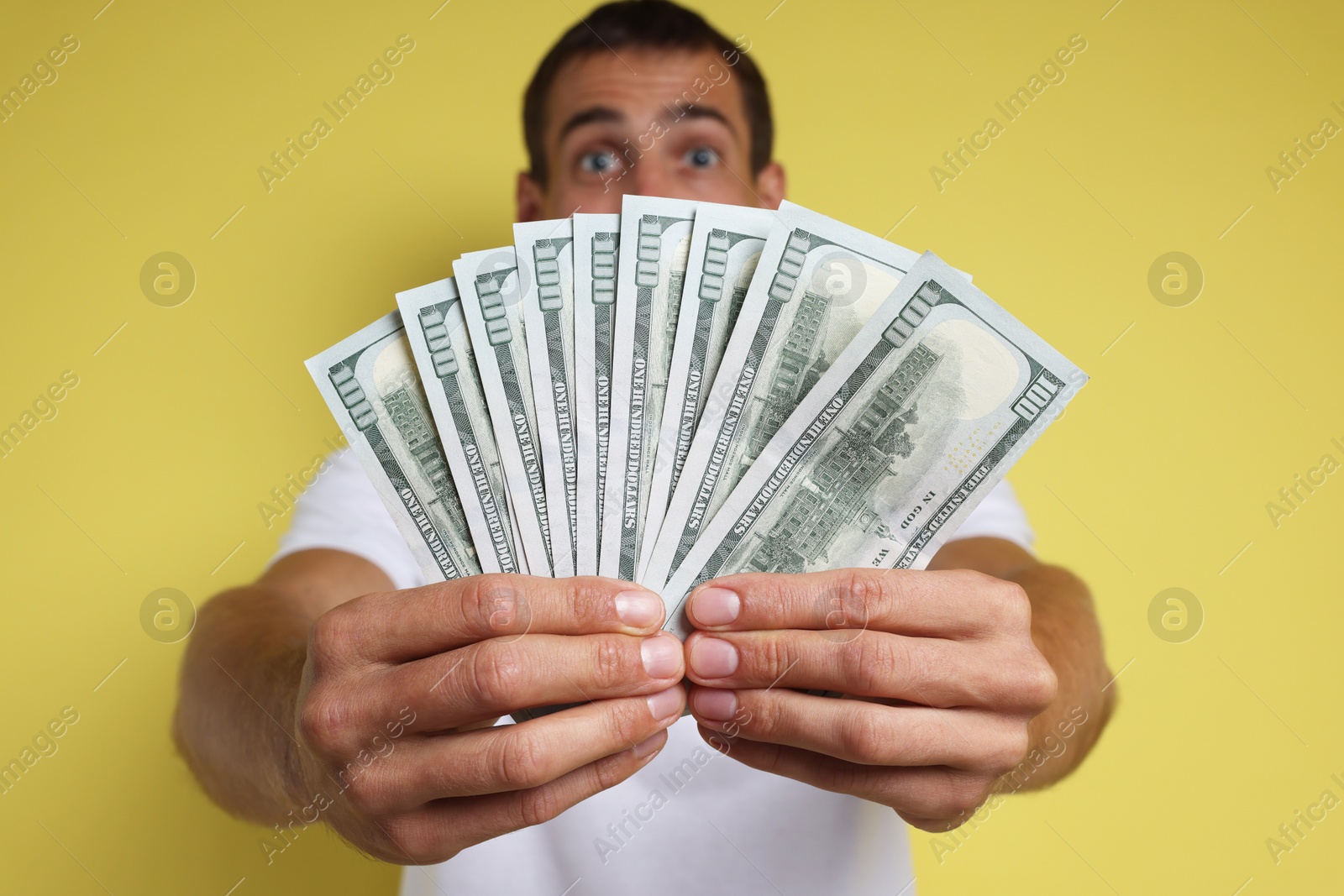 Photo of Man with dollar banknotes on yellow background, selective focus