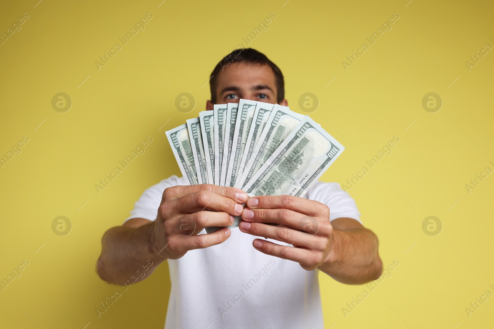 Photo of Man with dollar banknotes on yellow background, selective focus