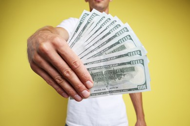 Man with dollar banknotes on yellow background, closeup