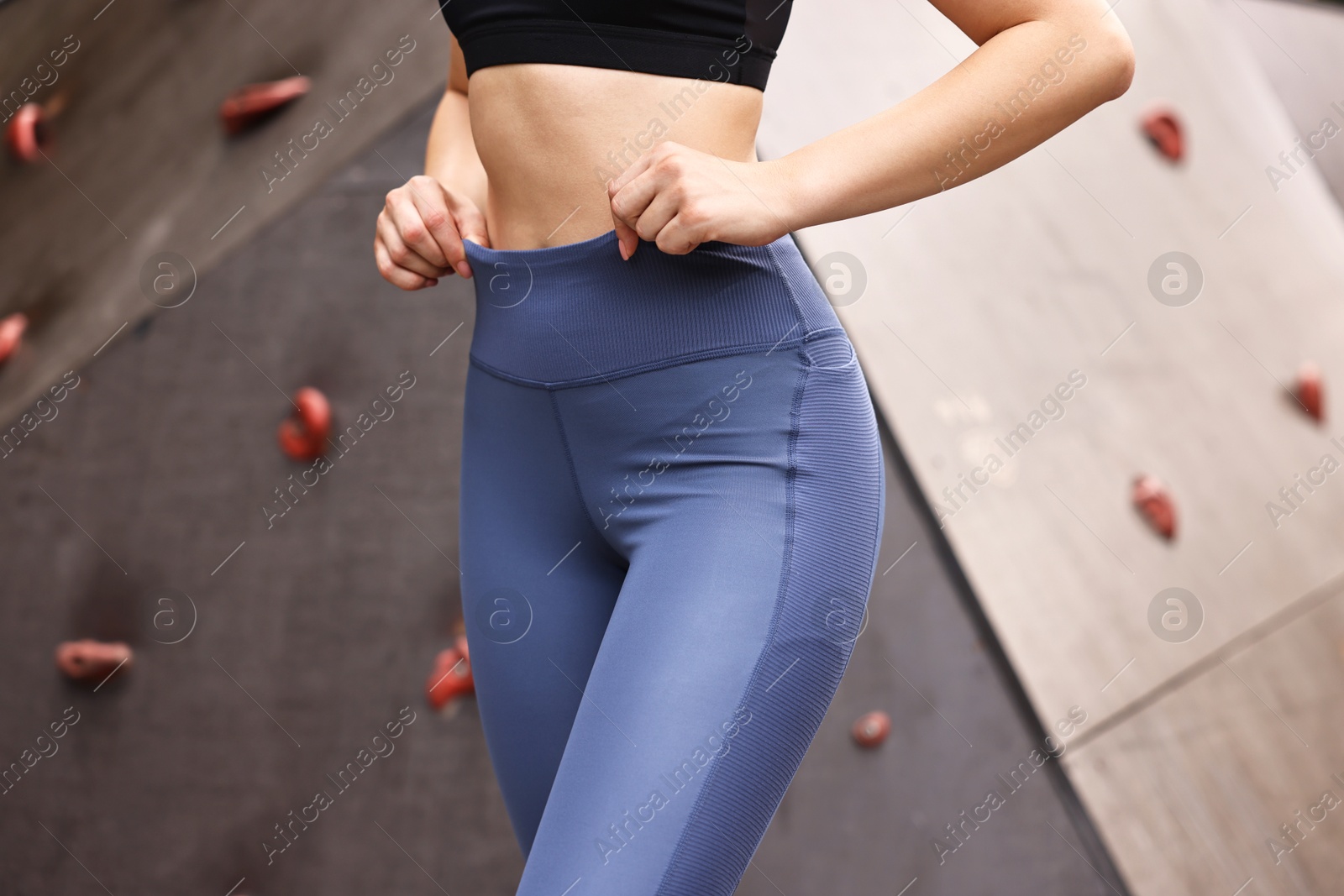 Photo of Woman wearing sports leggings near climbing wall outdoors, closeup