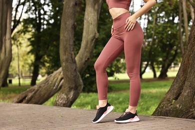 Photo of Woman wearing sports leggings outdoors, closeup. Space for text