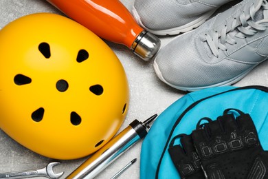 Photo of Bicycle helmet, backpack, gloves and other tools on light grey table, flat lay