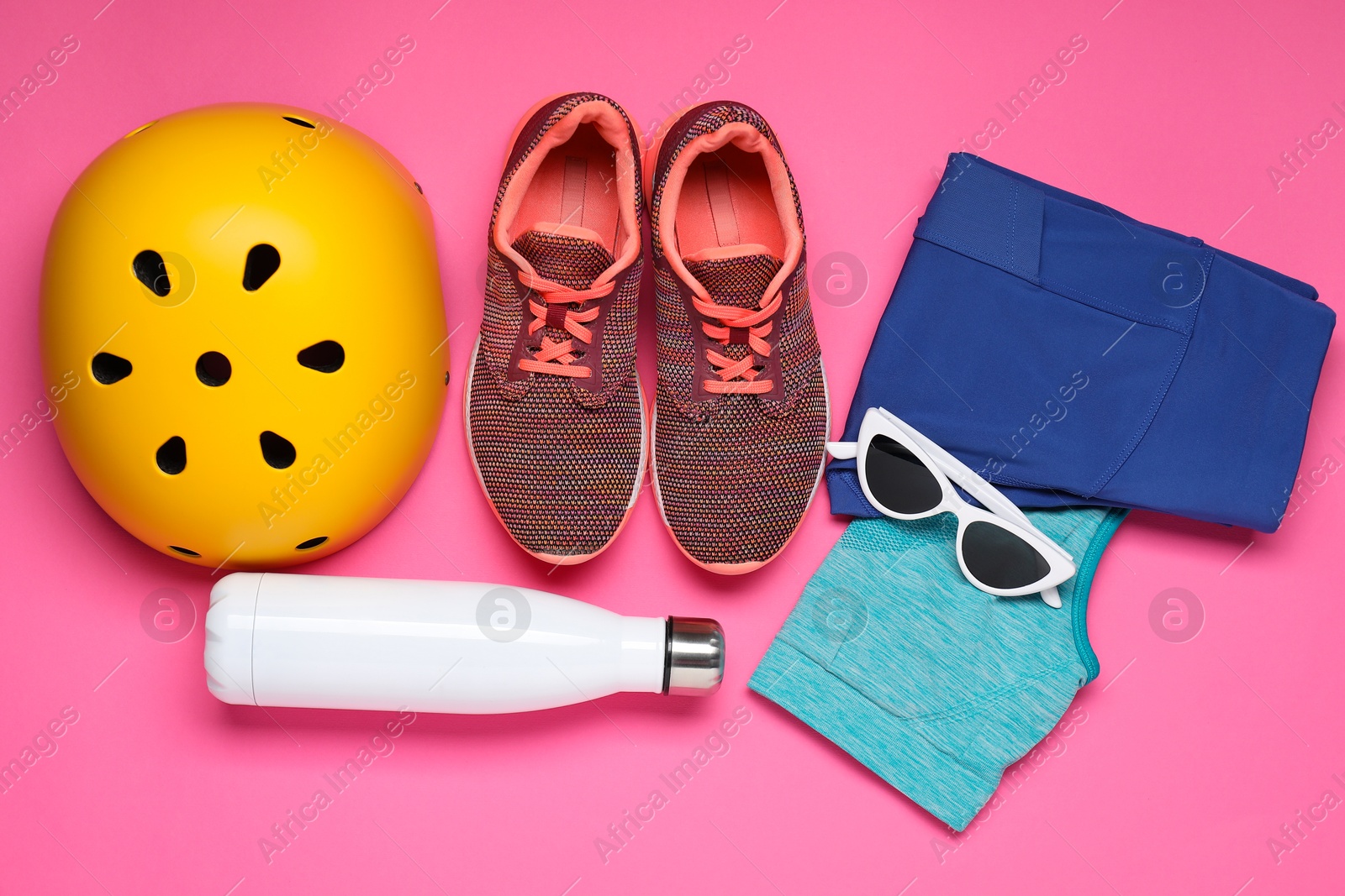 Photo of Bicycle helmet, sportswear, sneakers and accessories on pink background, flat lay