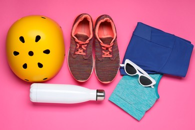 Photo of Bicycle helmet, sportswear, sneakers and accessories on pink background, flat lay