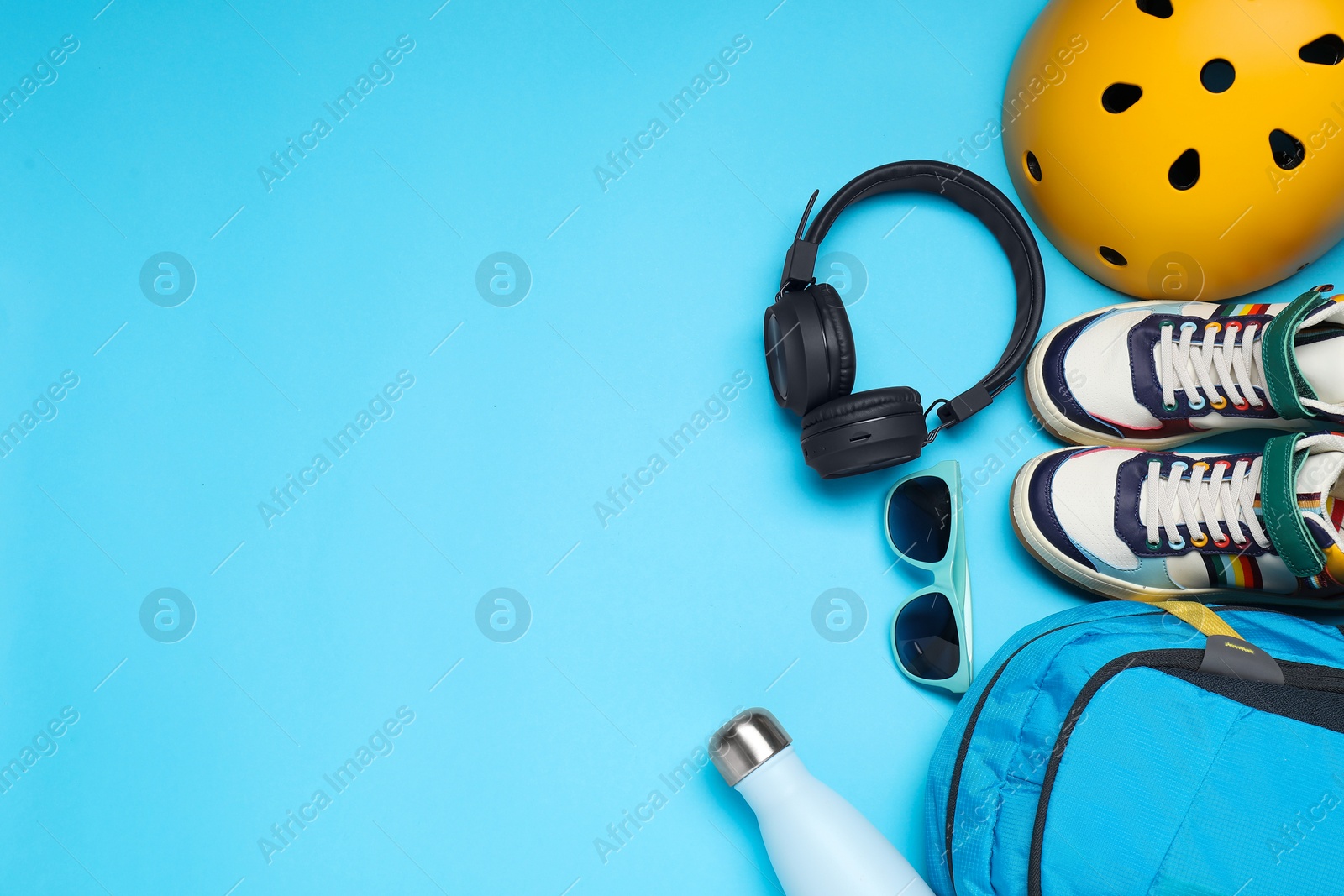 Photo of Bicycle helmet, accessories and sneakers on light blue background, flat lay. Space for text