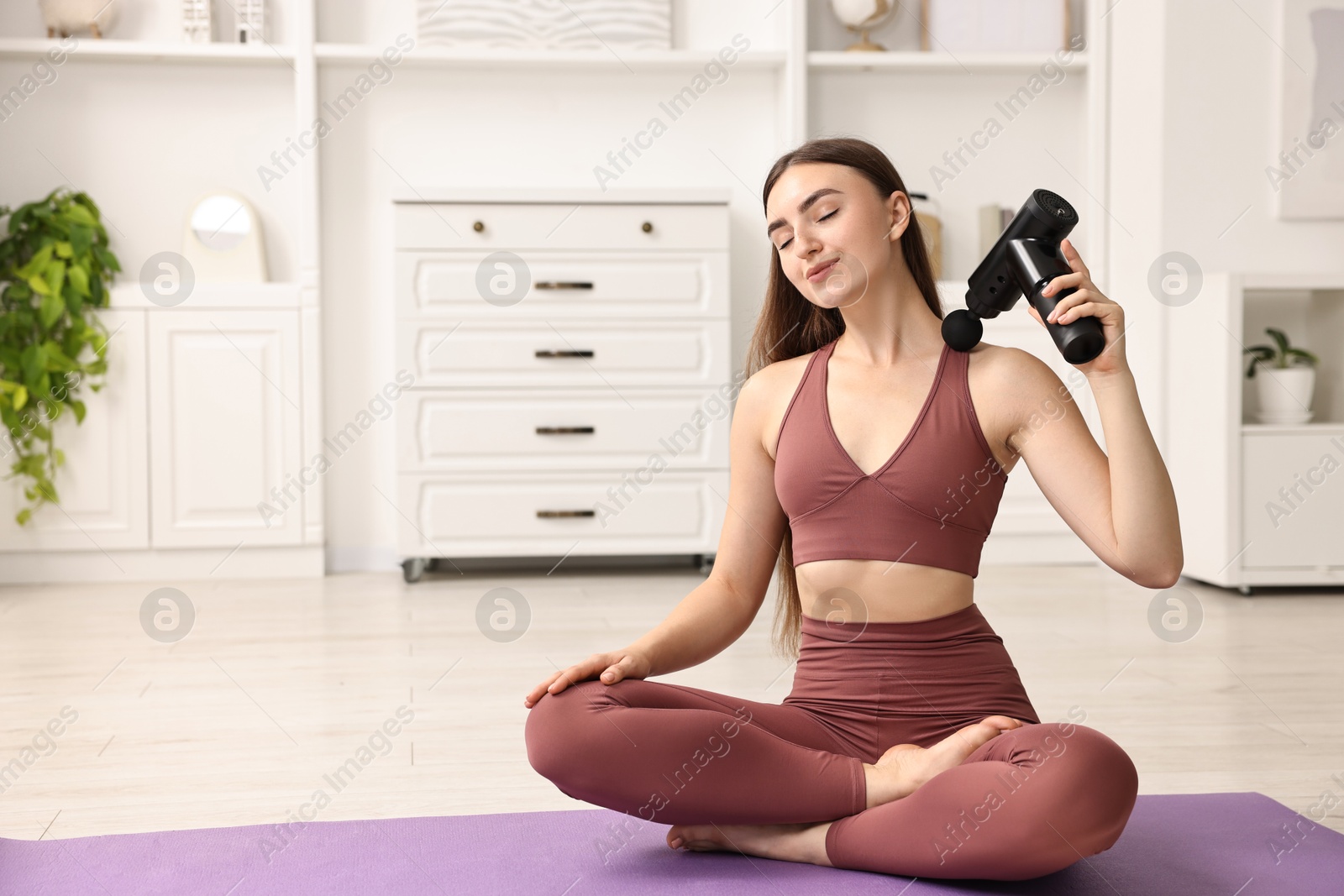 Photo of Woman using percussive massager to relieve trapezius muscle on mat at home. Space for text