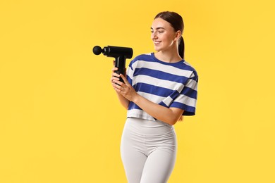 Photo of Young woman with percussive massager on yellow background