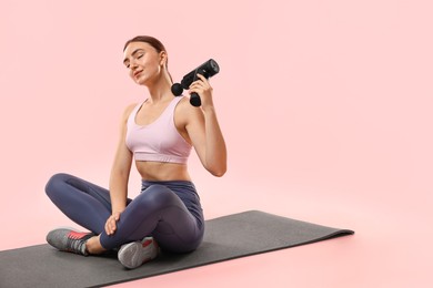 Woman using percussive massager to relieve trapezius muscle on pink background. Space for text