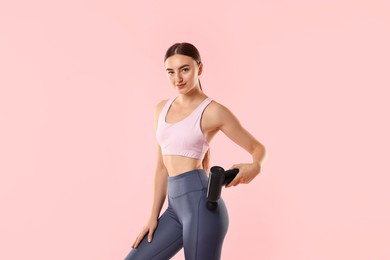 Photo of Woman using percussive massager to relax hip muscles on pink background