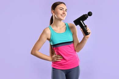 Photo of Young woman with percussive massager on light purple background