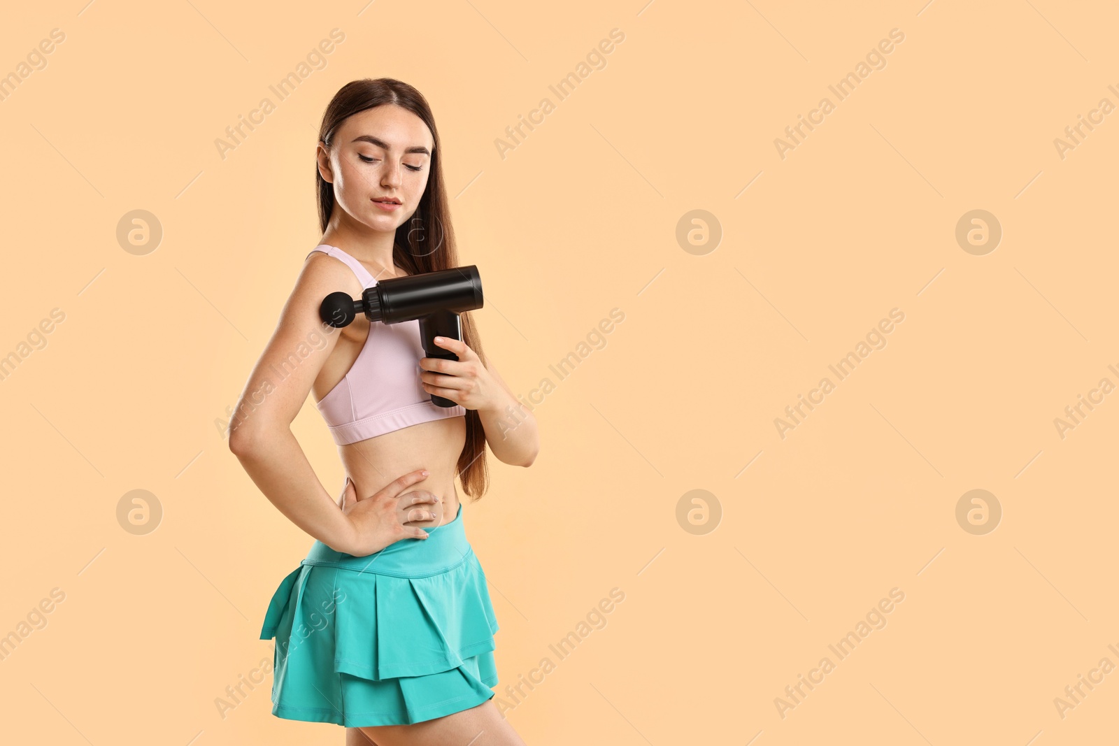 Photo of Woman using percussive massager to relieve arm muscles on beige background. Space for text