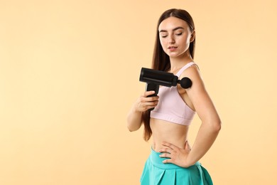 Woman using percussive massager to relieve arm muscles on beige background. Space for text