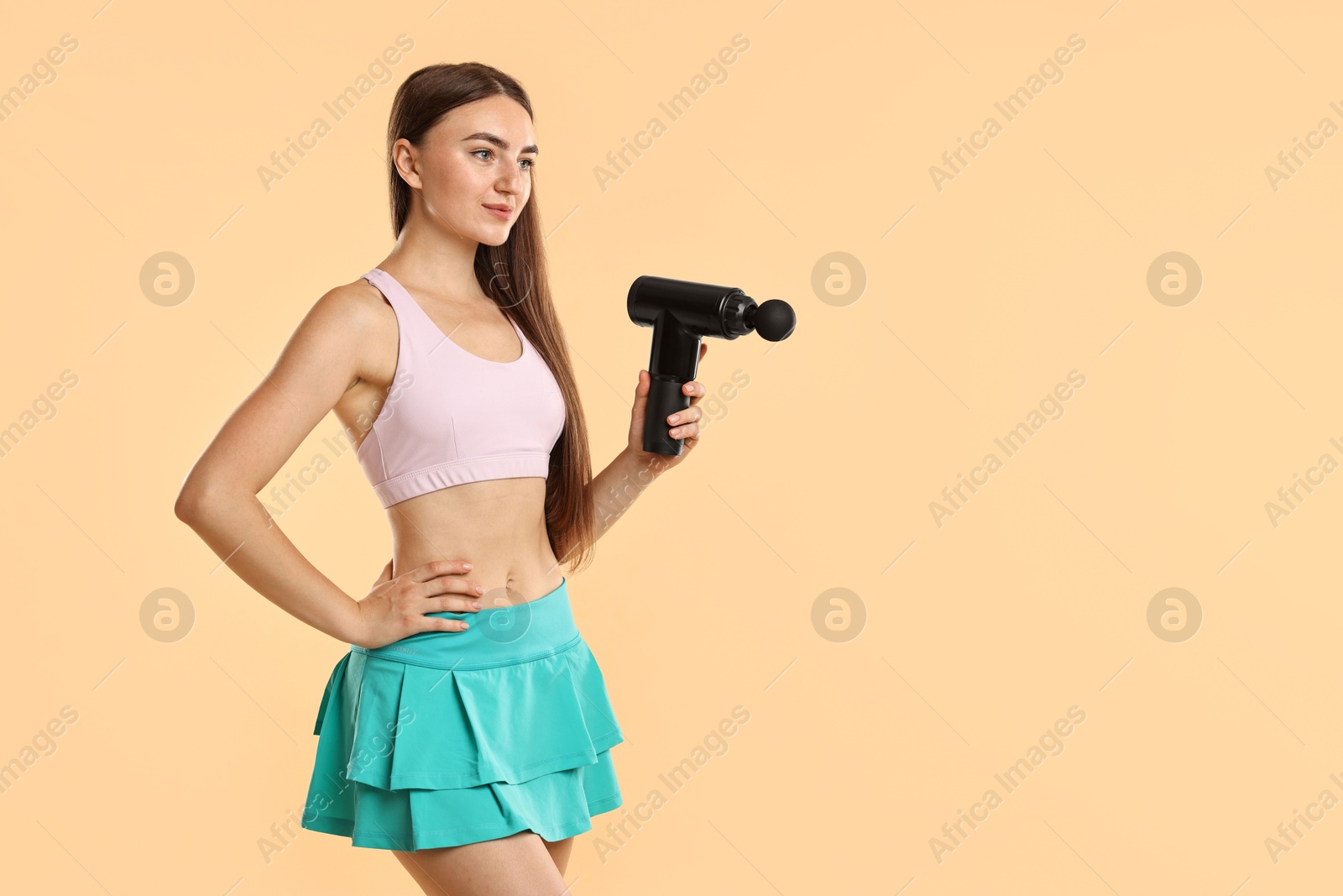 Photo of Young woman with percussive massager on beige background. Space for text