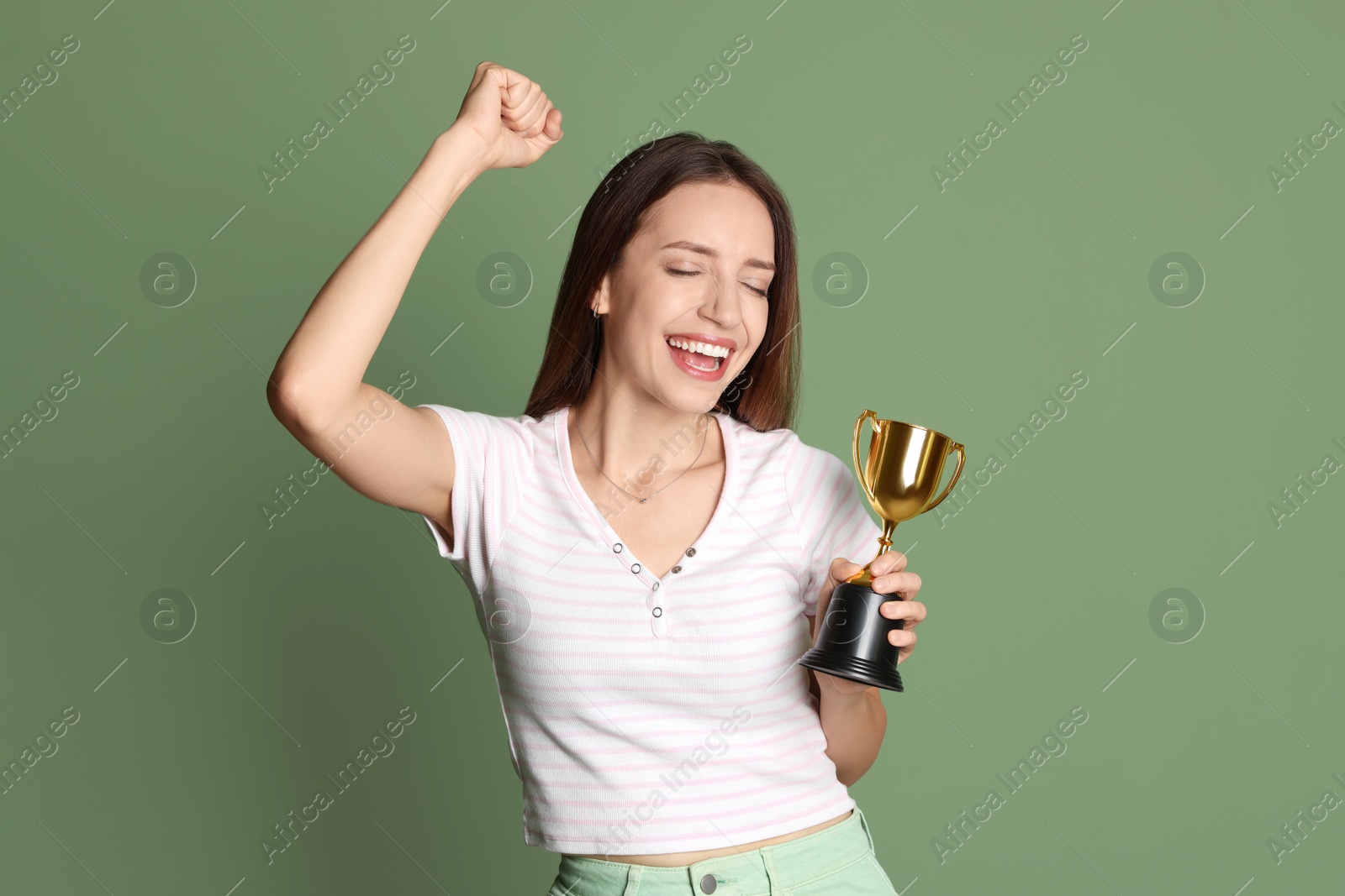 Photo of Happy winner with gold trophy cup on green background