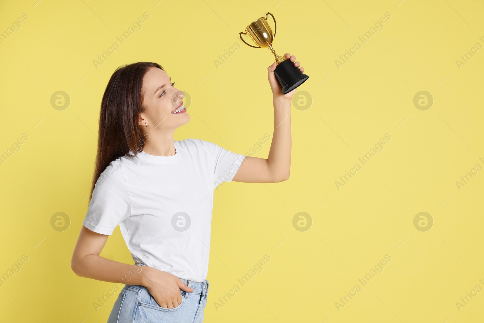 Photo of Happy winner with gold trophy cup on yellow background