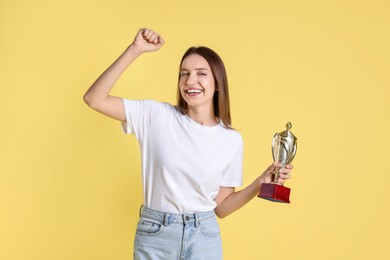 Happy winner with gold trophy cup on yellow background