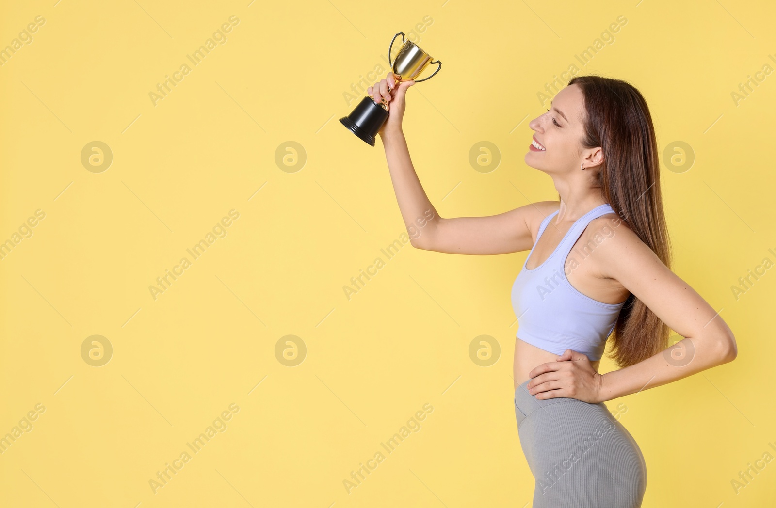 Photo of Happy winner with gold trophy cup on yellow background, space for text