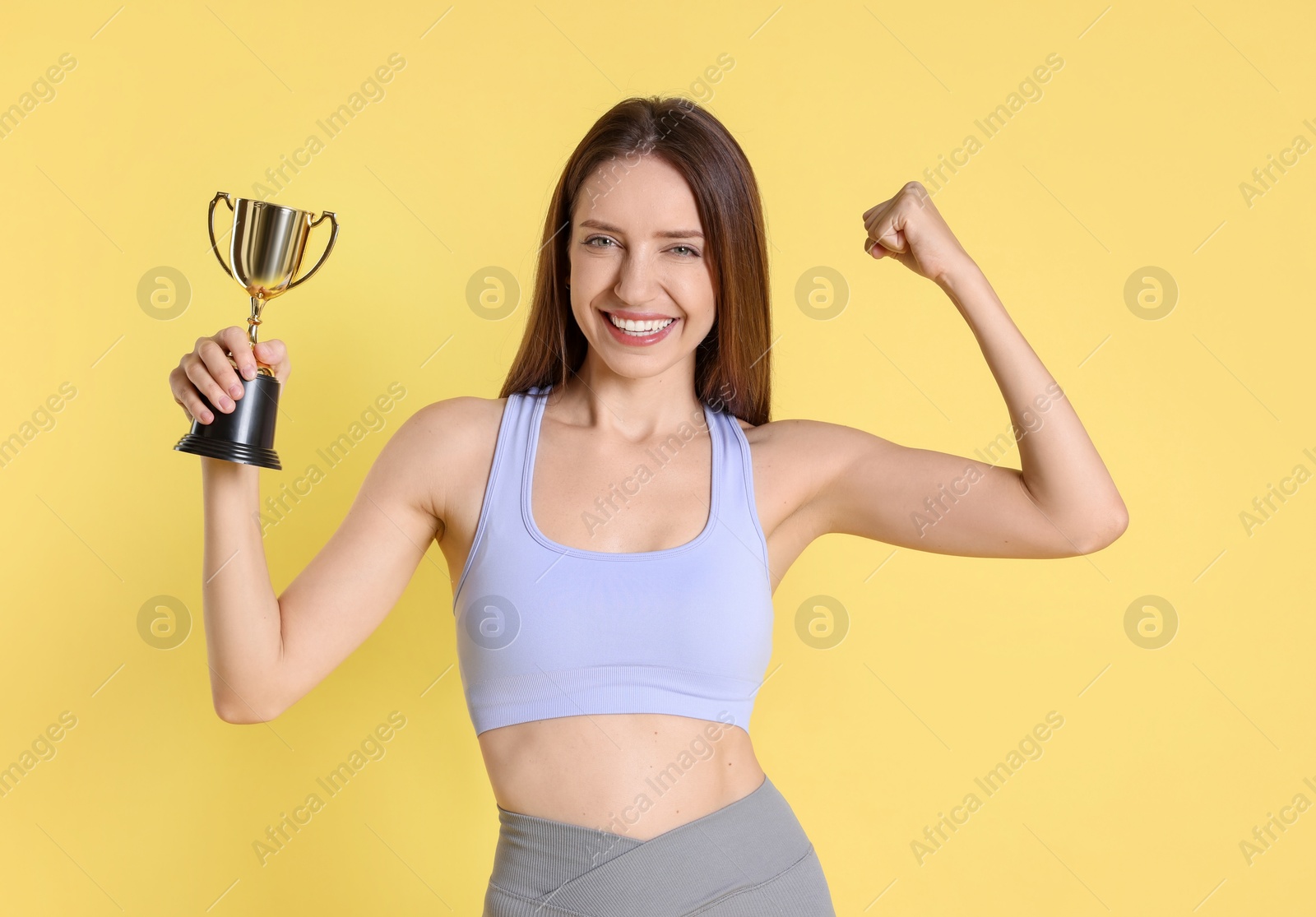 Photo of Happy winner with gold trophy cup on yellow background