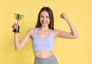 Photo of Happy winner with gold trophy cup on yellow background