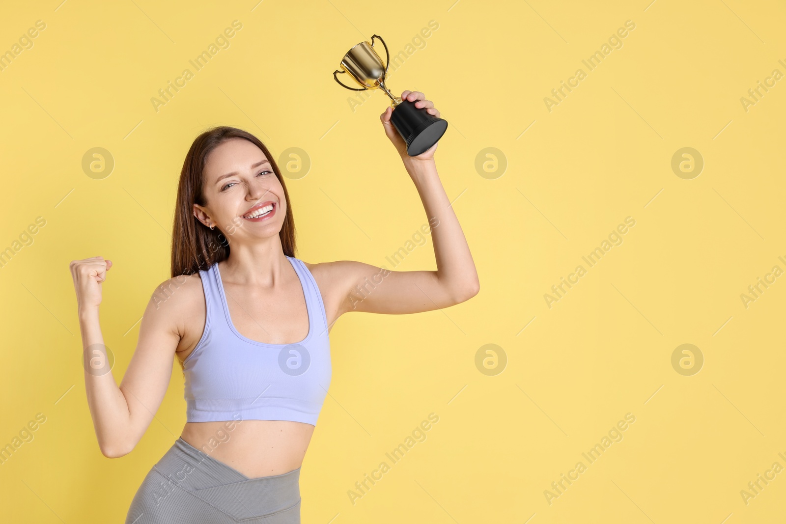 Photo of Happy winner with gold trophy cup on yellow background, space for text