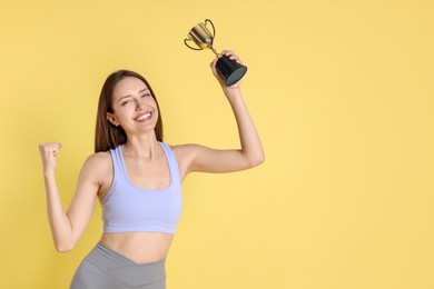 Photo of Happy winner with gold trophy cup on yellow background, space for text