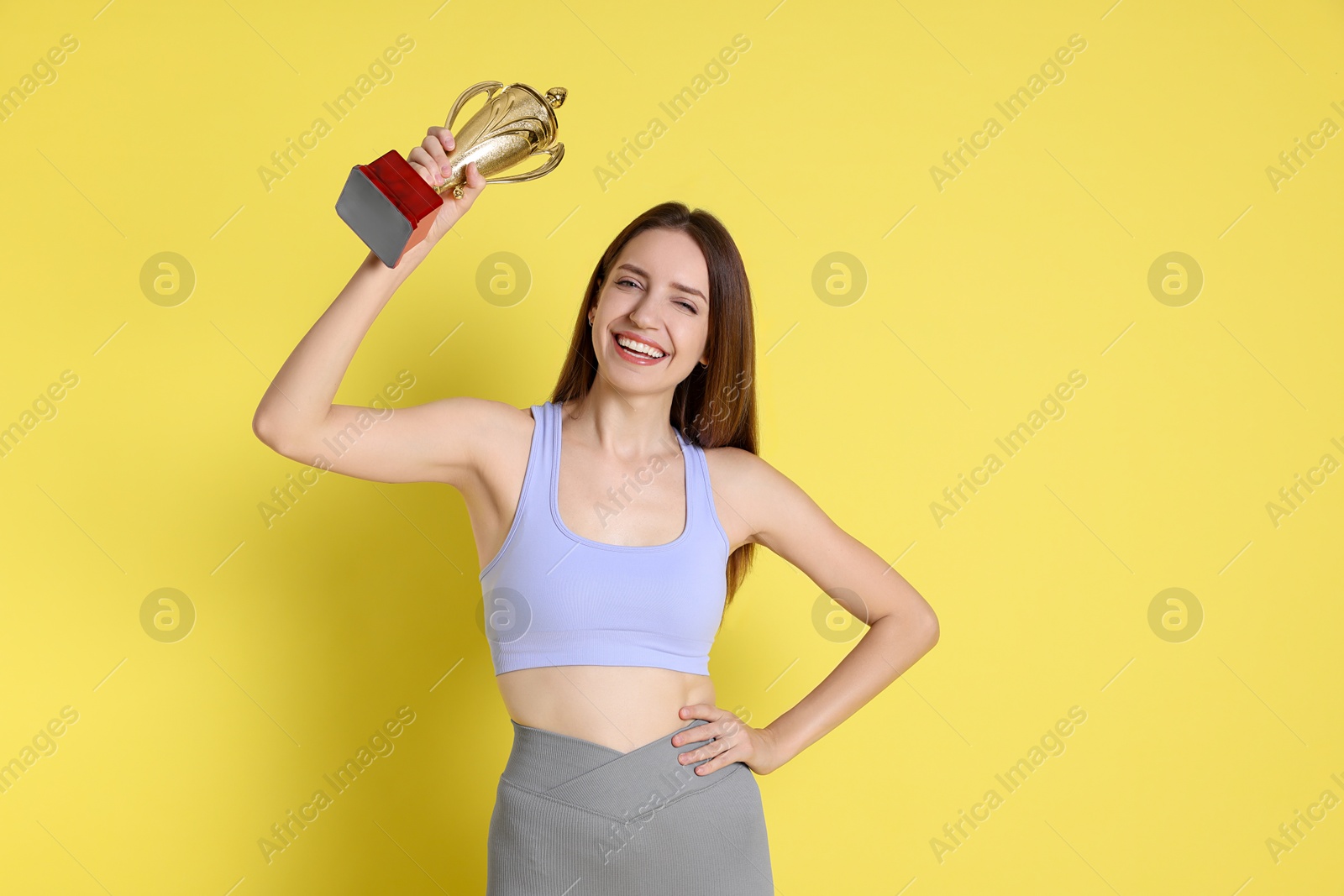 Photo of Happy winner with gold trophy cup on yellow background