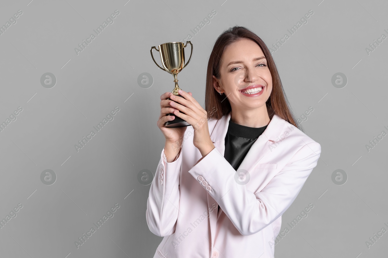 Photo of Happy winner with gold trophy cup on gray background