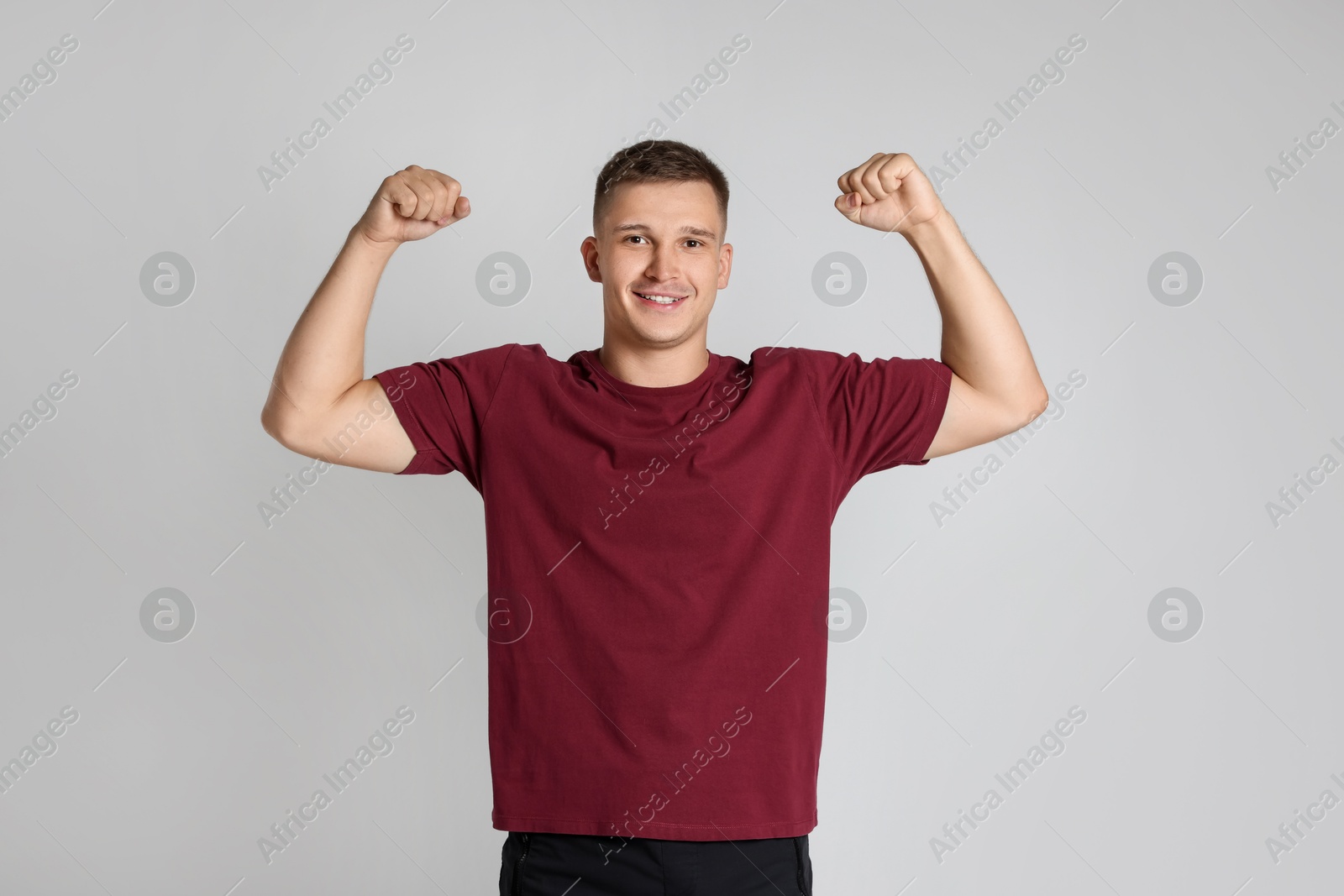 Photo of Happy winner showing his biceps on light grey background