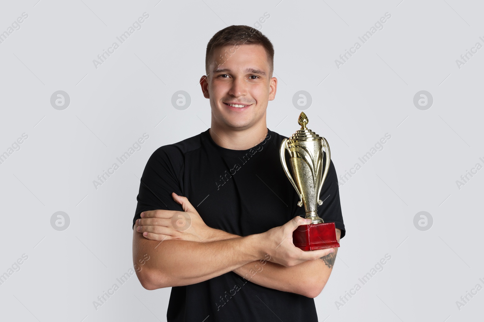 Photo of Happy winner with golden trophy cup on light grey background