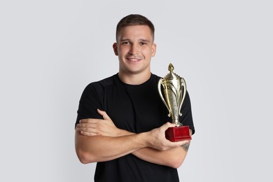 Photo of Happy winner with golden trophy cup on light grey background