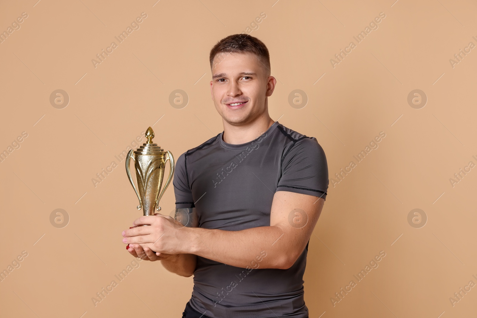 Photo of Happy winner with golden trophy cup on beige background