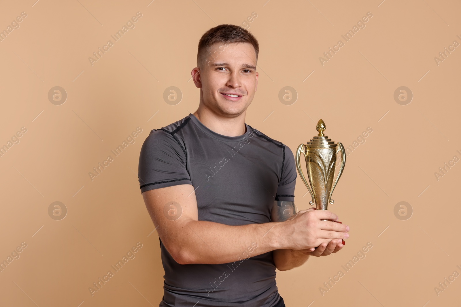 Photo of Happy winner with golden trophy cup on beige background