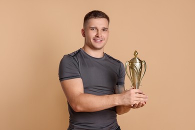 Happy winner with golden trophy cup on beige background