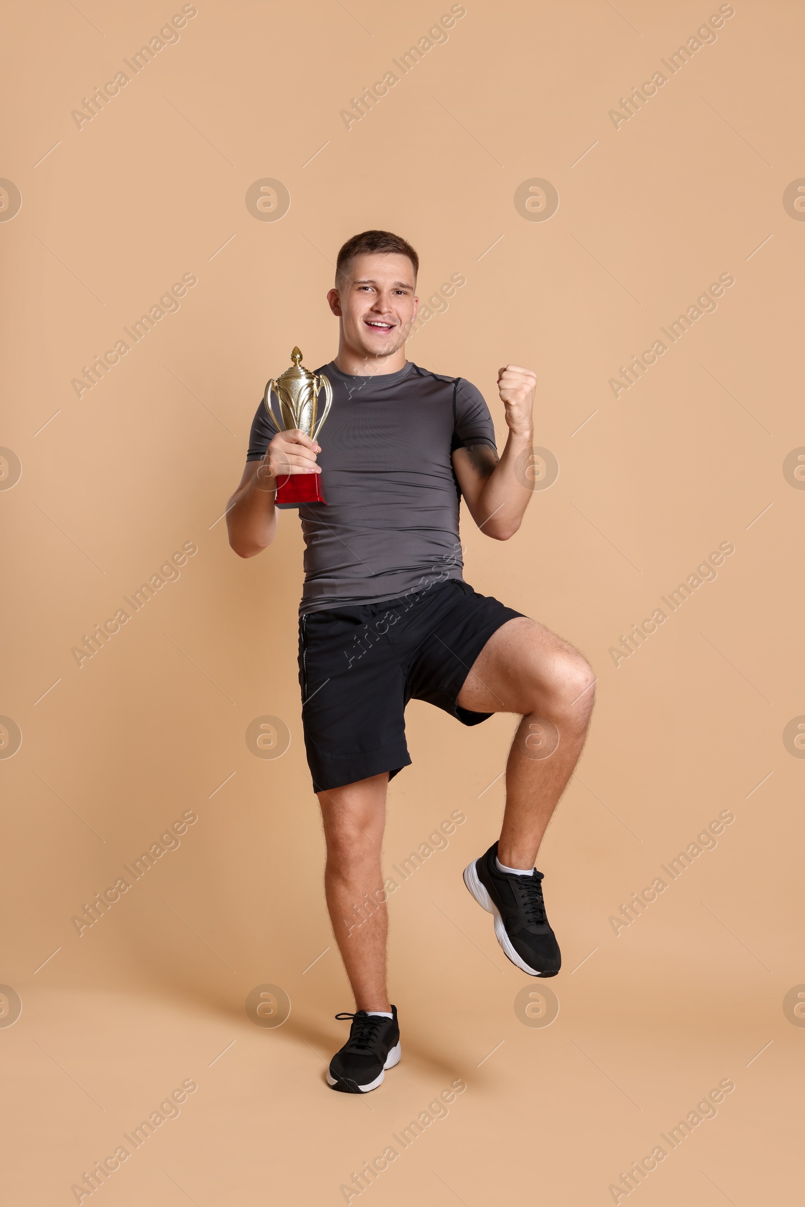 Photo of Happy winner with golden trophy cup on beige background