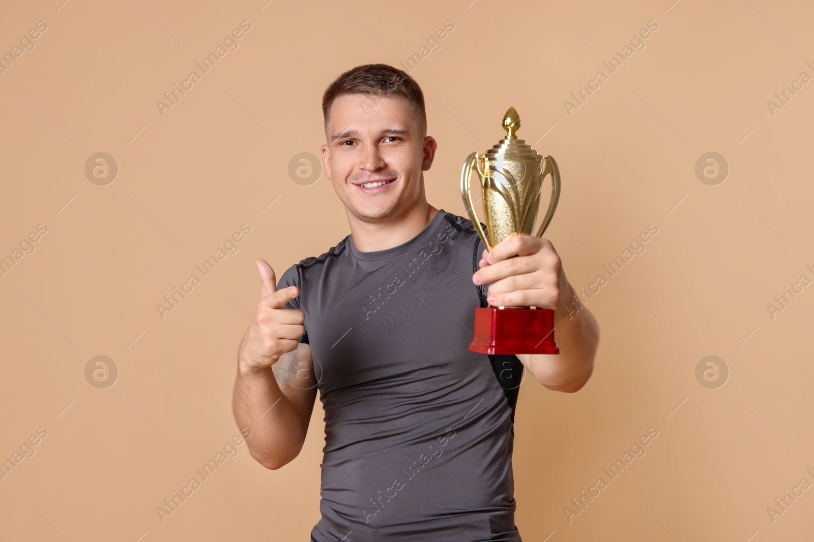 Photo of Happy winner with golden trophy cup on beige background