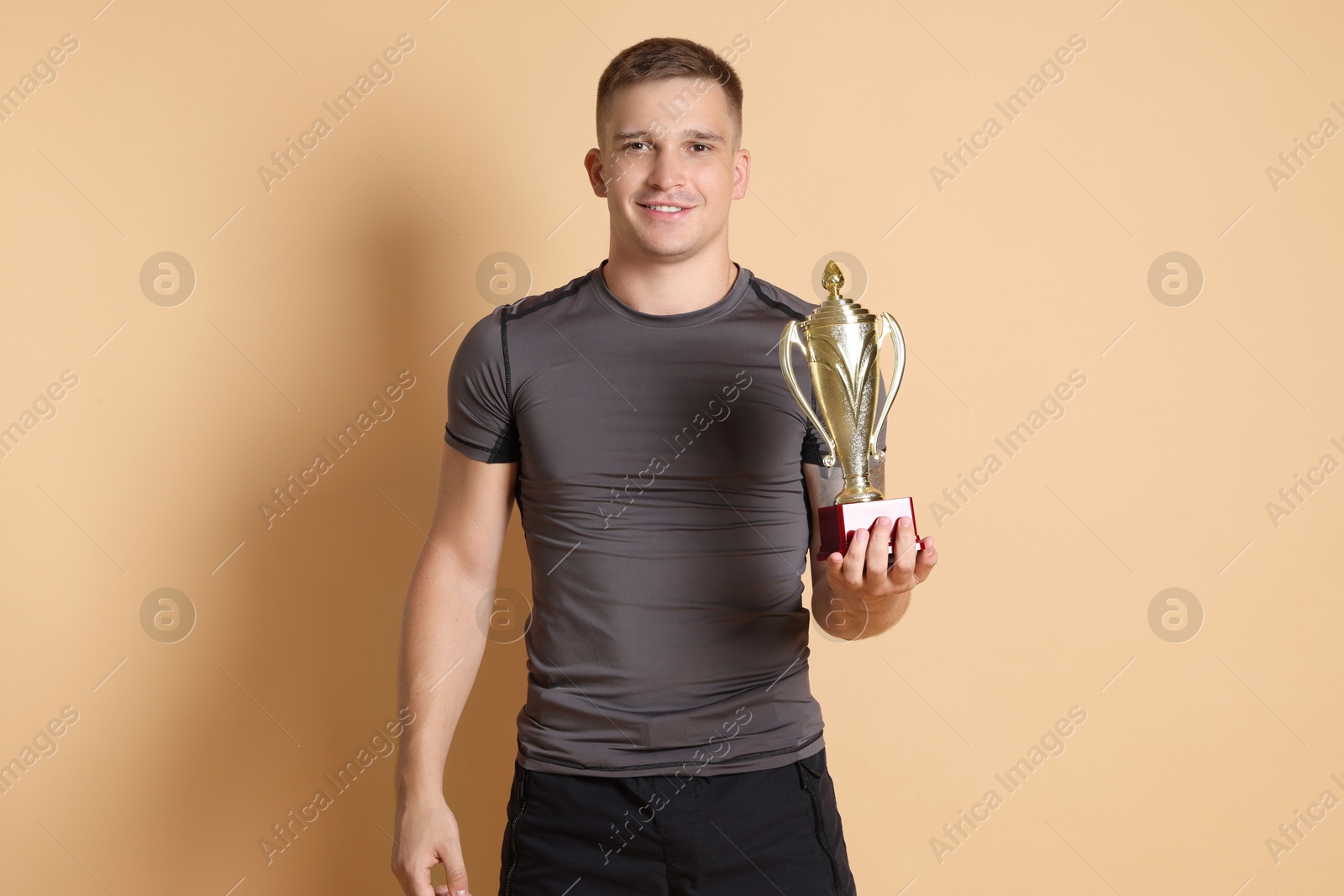 Photo of Happy winner with golden trophy cup on beige background