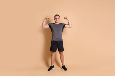 Photo of Happy winner showing his biceps on beige background