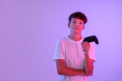 Teenage boy with controller on violet background. Space for text