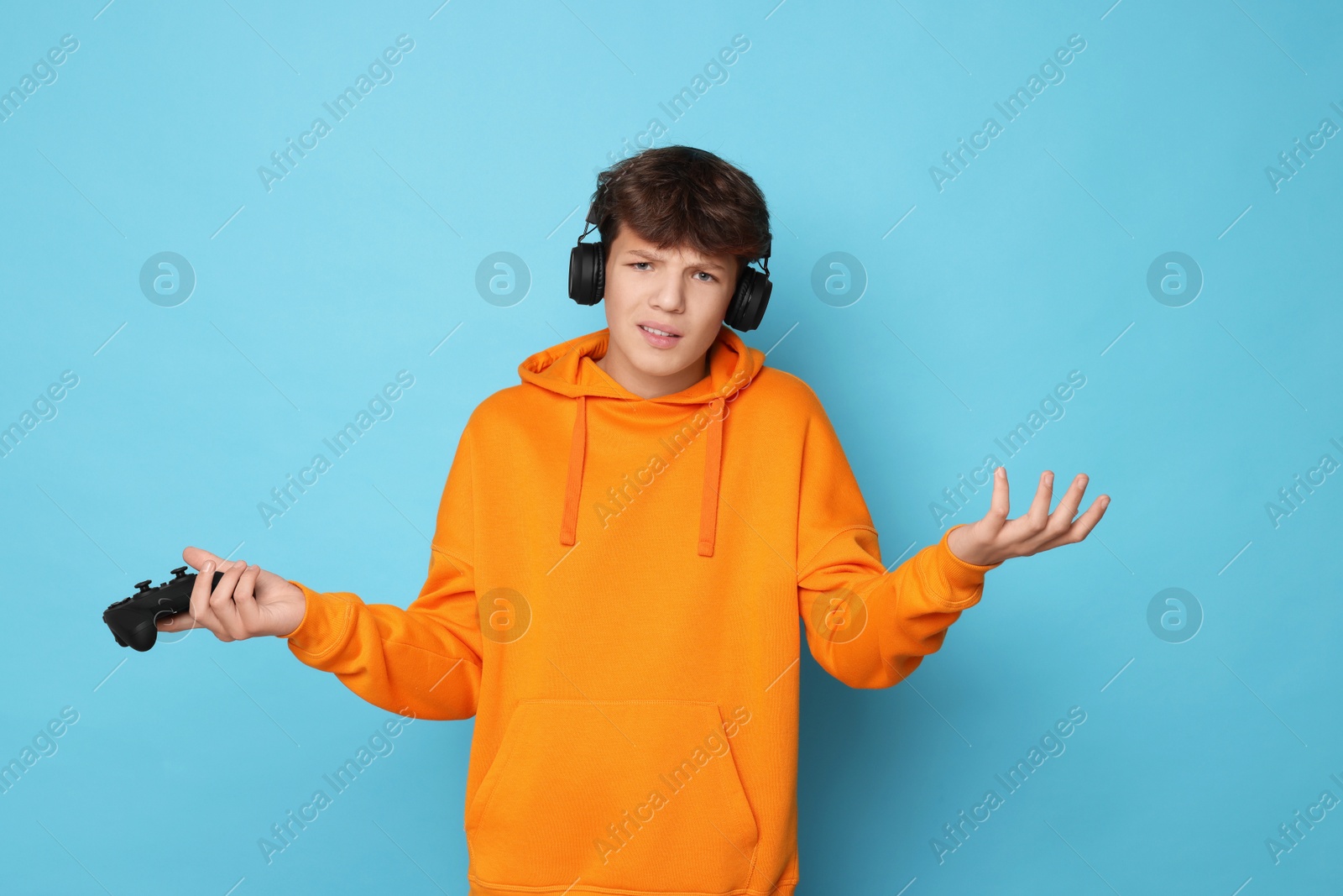 Photo of Teenage boy with controller on light blue background