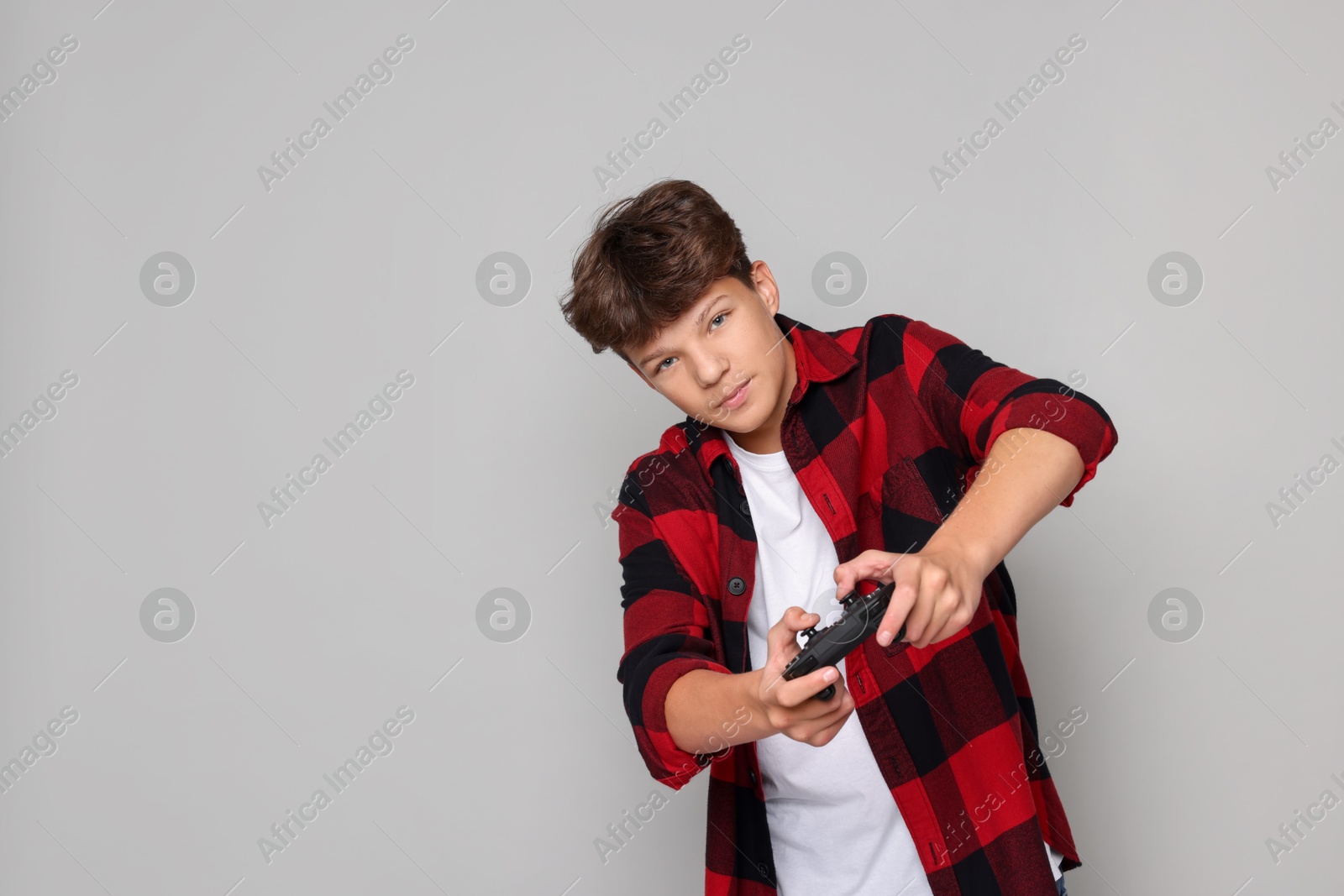 Photo of Teenage boy playing video game with controller on grey background. Space for text