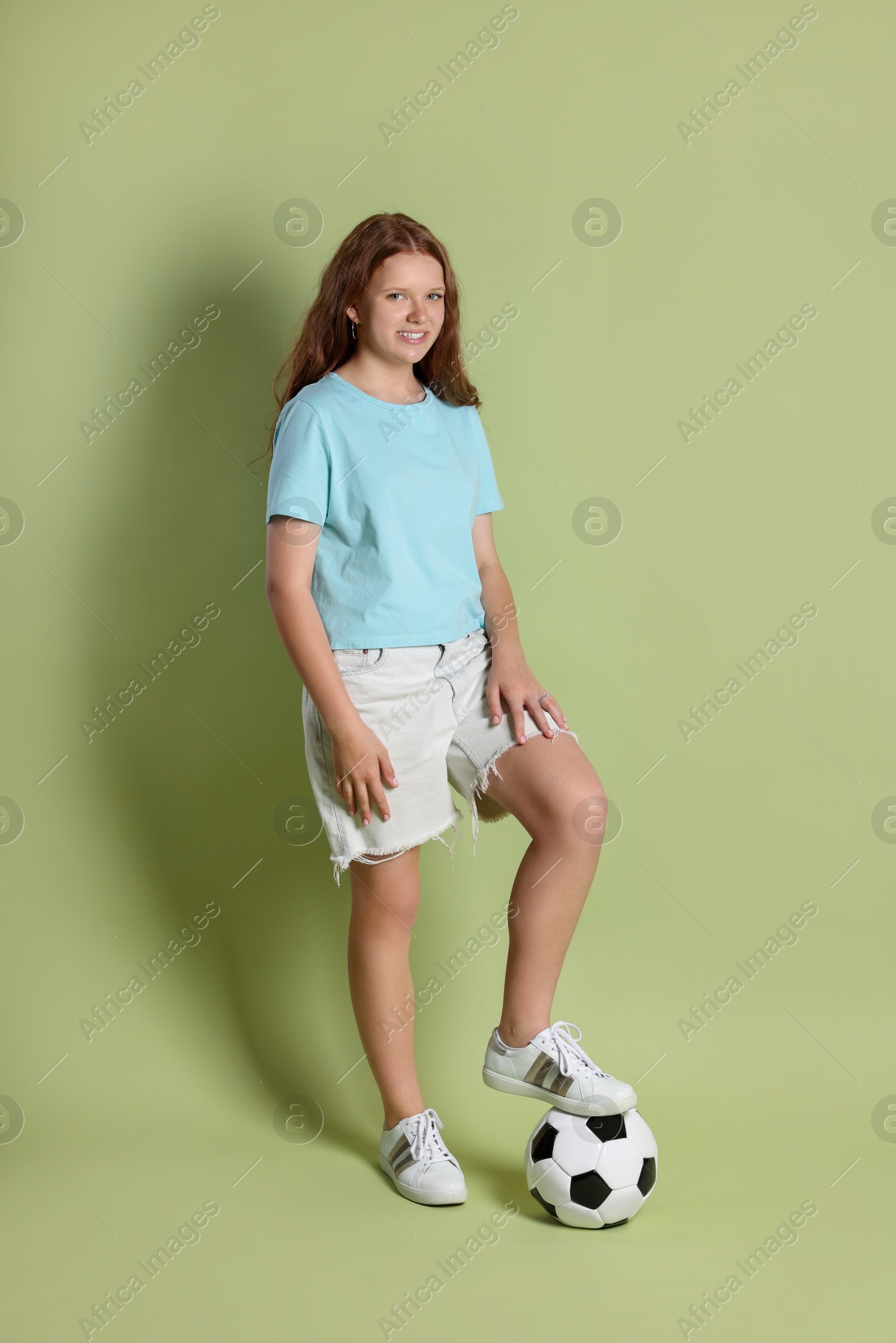 Photo of Smiling teenage girl with soccer ball on green background